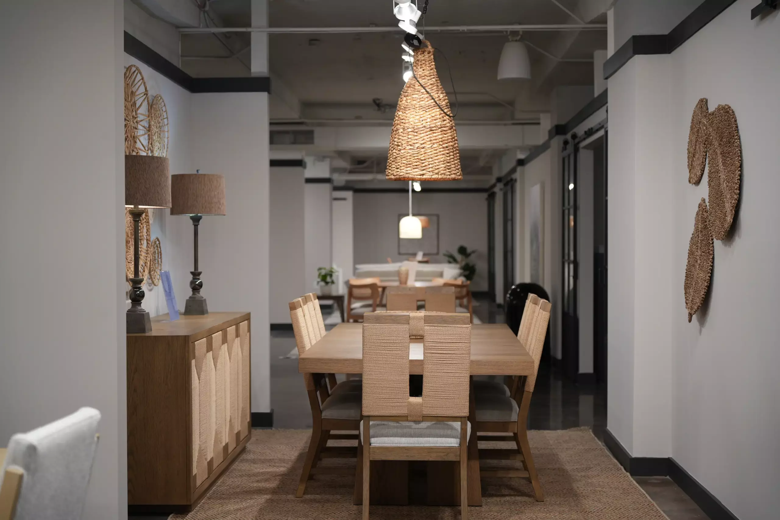Light oak dining table with woven rope-back chairs and sideboard showroom display
